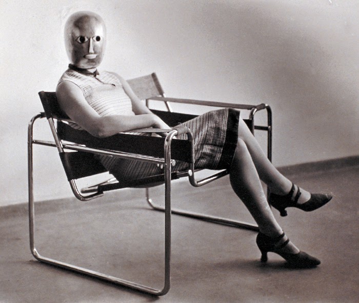 A Bauhaus group effort: Woman in B3 club chair by Marcel Breuer, wearing a mask by Oskar Schlemmer and a dress in fabric designed by Lis Beyer, 1926. Photograph by Erich ConsemÃ¼ller.